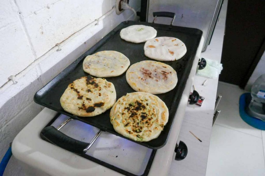 Salvadoran pupusas cooking on a griddle.