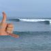 Surfing El Salvador wave El Sunzal. Shaka hand signal infront of breaking waves.
