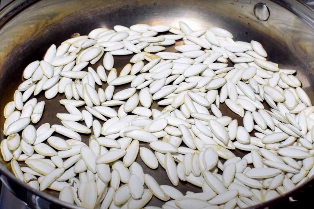 Pumpkin seeds toasting. Toasting pumpkin seeds with the husk on in a pan